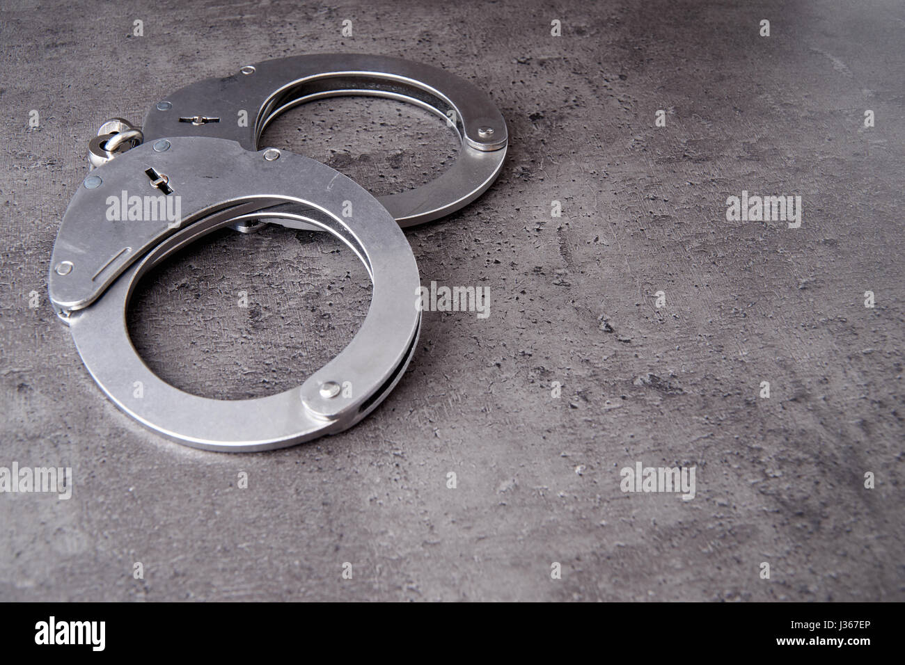 German police handcuffs on rough grey background with copy space. Stock Photo