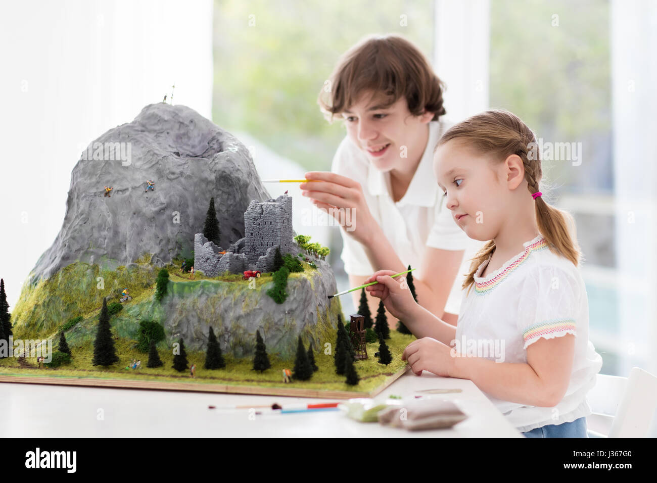 Children work on model building school project. Kids build miniature scale model mountain for