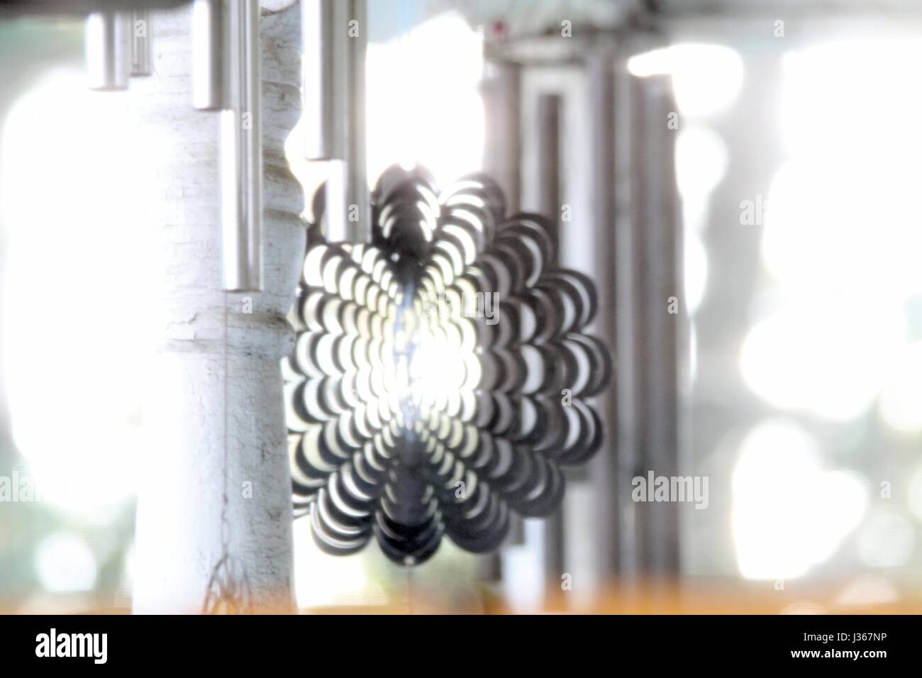 Wind chimes and wind spinners catch the light. Stock Photo