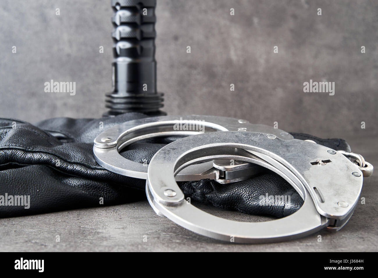 German police handcuffs, leather gloves and a torchlight on rough grey background with copy space. Stock Photo