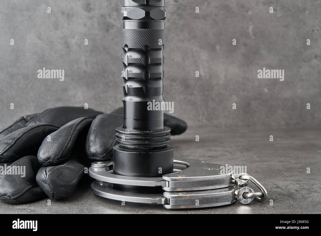 German police handcuffs, leather gloves and a torchlight on rough grey background with copy space. Stock Photo