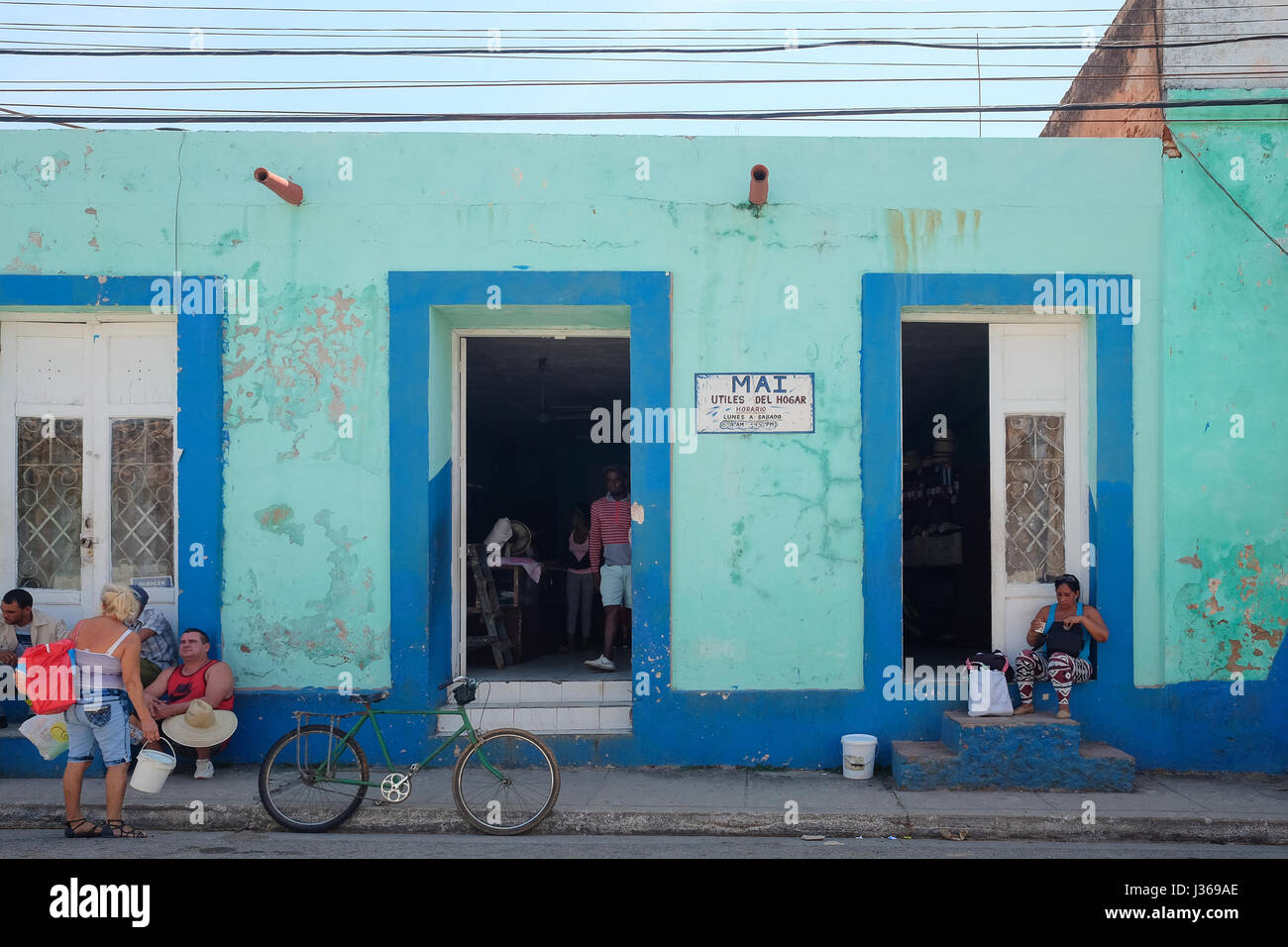 Local street life in Trinidad, Sancti Spiritus, Cuba. People gathering in front of a shop. Stock Photo