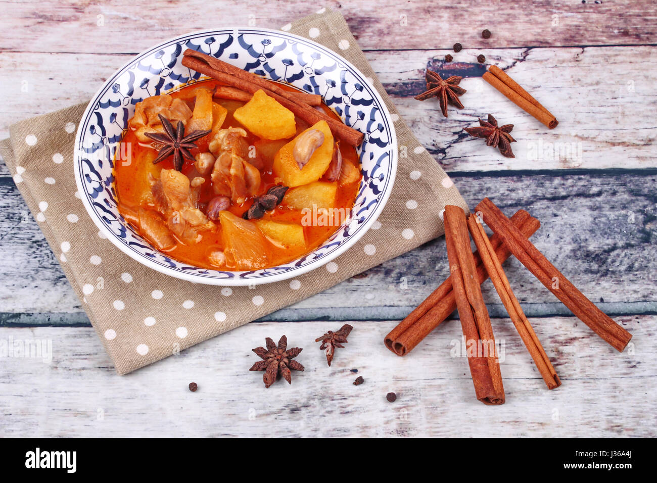 Thai massaman curry paste recipe served in Thai pattern bowl and herbs on wood Stock Photo