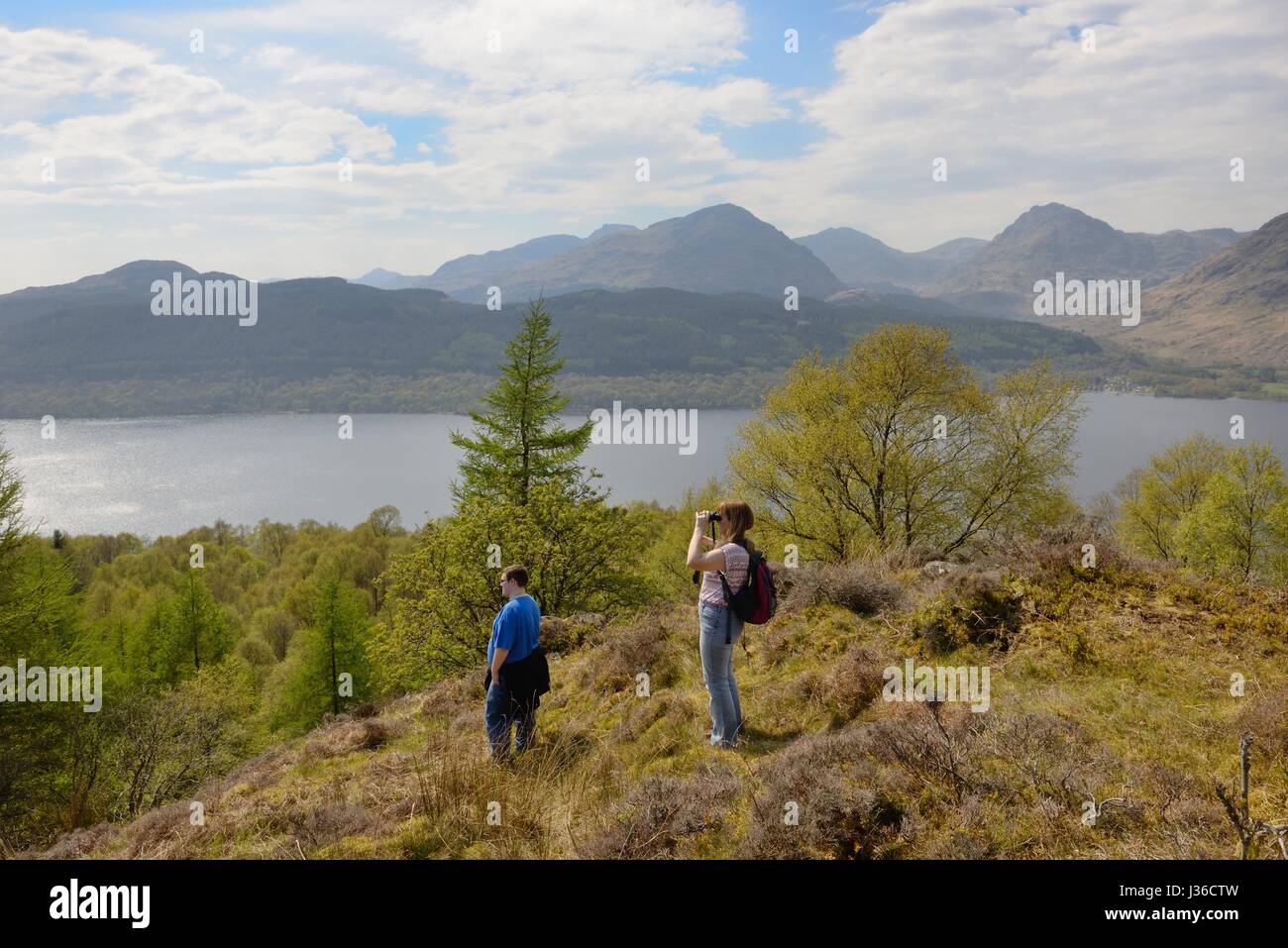 A couple gaze over Loch Lomond from a hilltop near Inversnaid, Scotland, UK Stock Photo