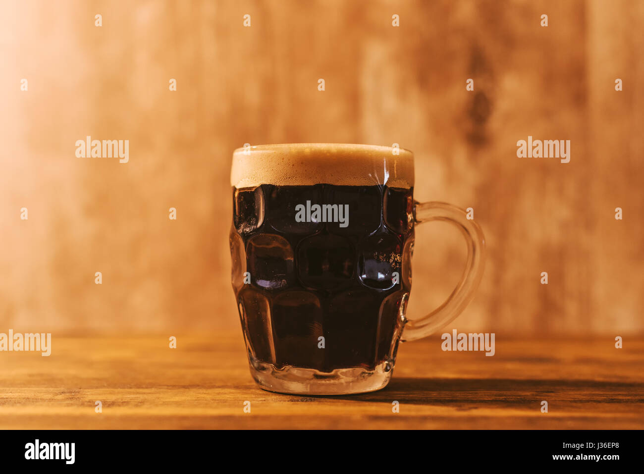 Dark craft beer in british dimpled glass pint mug on bar table Stock Photo