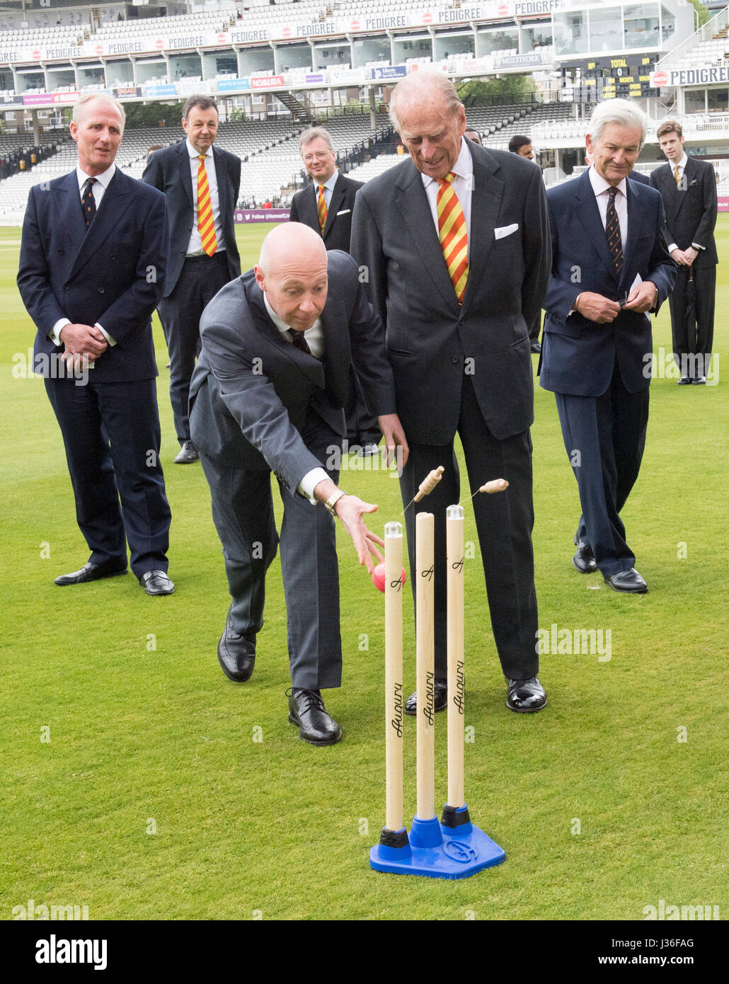The Duke of Edinburgh (second right) watches as Marylebone Cricket Club's Laws of Cricket Manager Fraser Stewart (right) bowls towards self retracting bails at Lord's Cricket Ground in London. Stock Photo