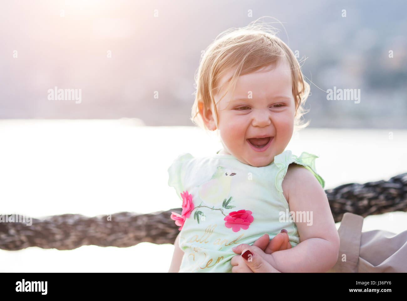 female 1 years old child smile and enjoy time with her mother at sunset Stock Photo