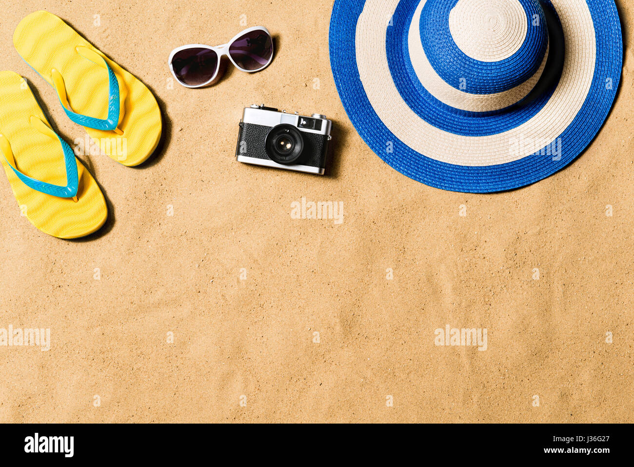 Pair of flip flop sandals, sunglasses, hat and camera. Stock Photo