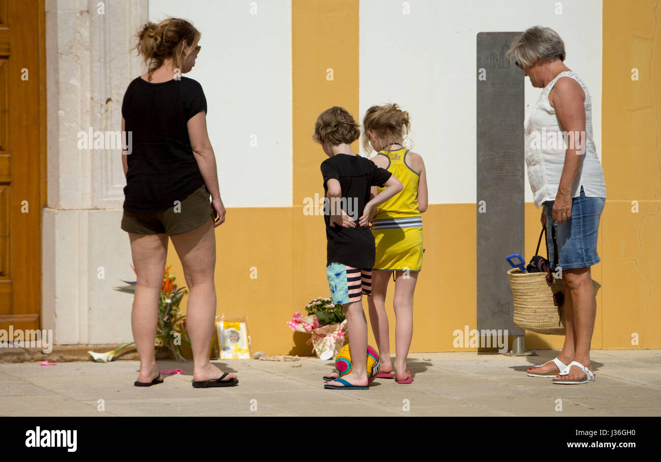 A family looks at tributes to Madeleine McCann outside the Church of Nossa Senhora da Luz in Praia Da Luz, Portugal, close to where Madeline McCann went missing from 10 years ago on May 3rd. Stock Photo