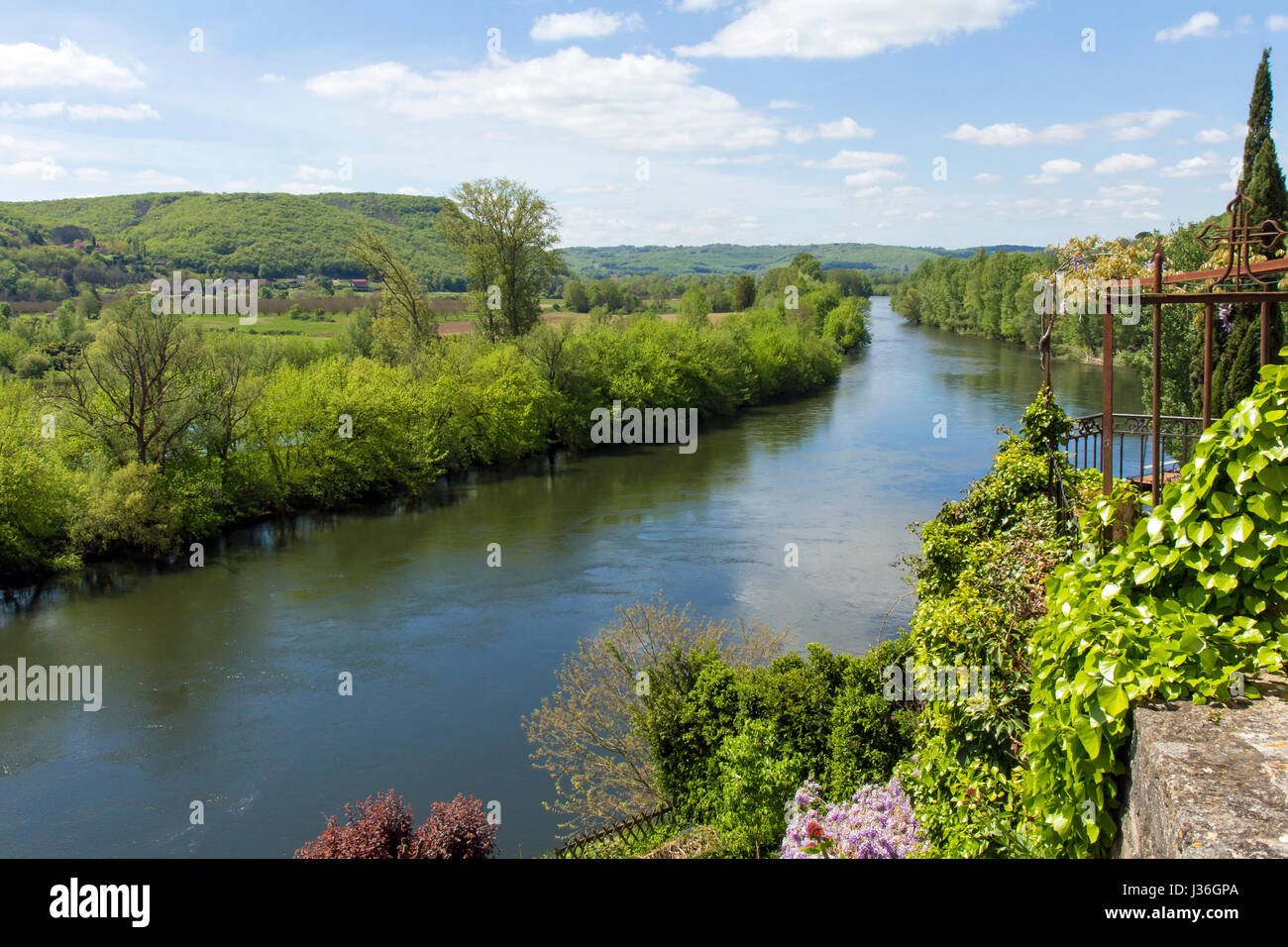 Perigord in summer with the Dordogne River flowing past banks of trees, shrubs and flowers Stock Photo