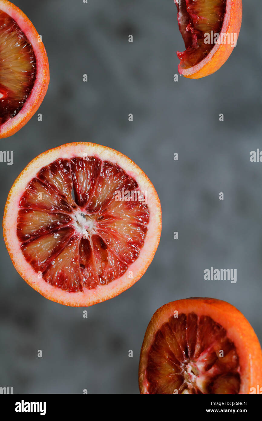 Abstract composition of pieces of bloody orange in weightlessness against a gray background. Stock Photo