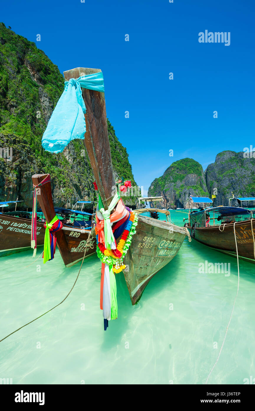 MAYA BAY, THAILAND - NOVEMBER 11, 2014: Traditional Thai longtail boats decorated with good luck bow sashes float on the shore of Maya Bay. Stock Photo