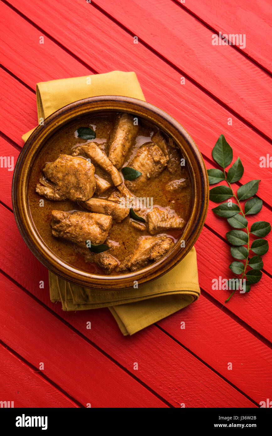 tasty fish curry served with white cooked basmati rice with curry leaves in the background
