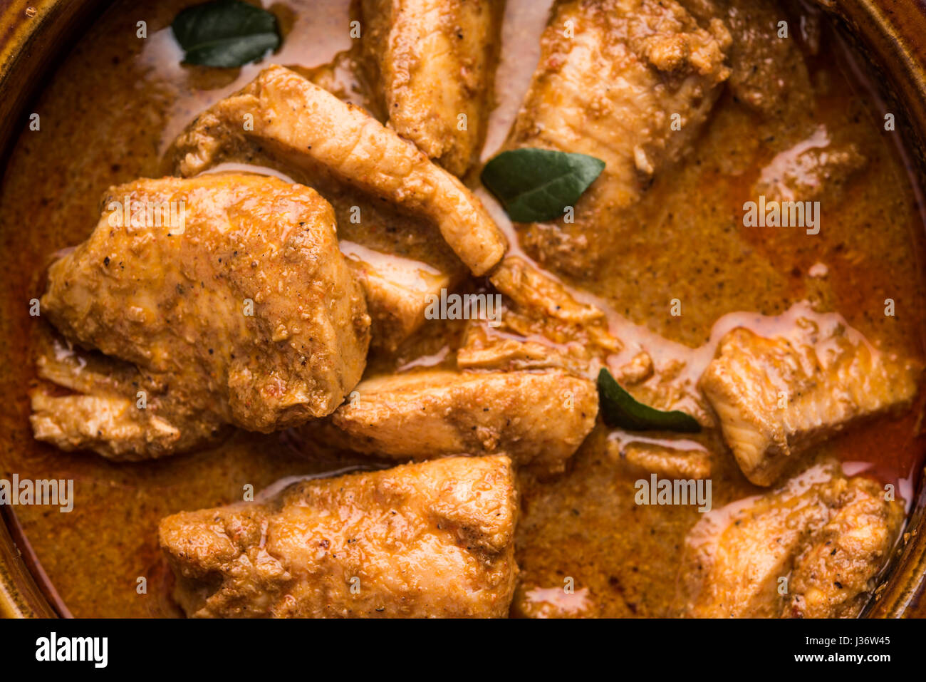 tasty fish curry served with white cooked basmati rice with curry leaves in the background