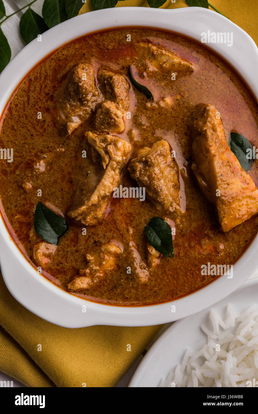 tasty fish curry served with white cooked basmati rice with curry leaves in the background