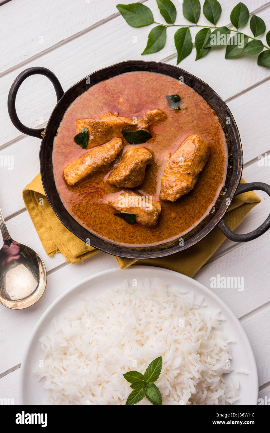 tasty fish curry served with white cooked basmati rice with curry leaves in the background
