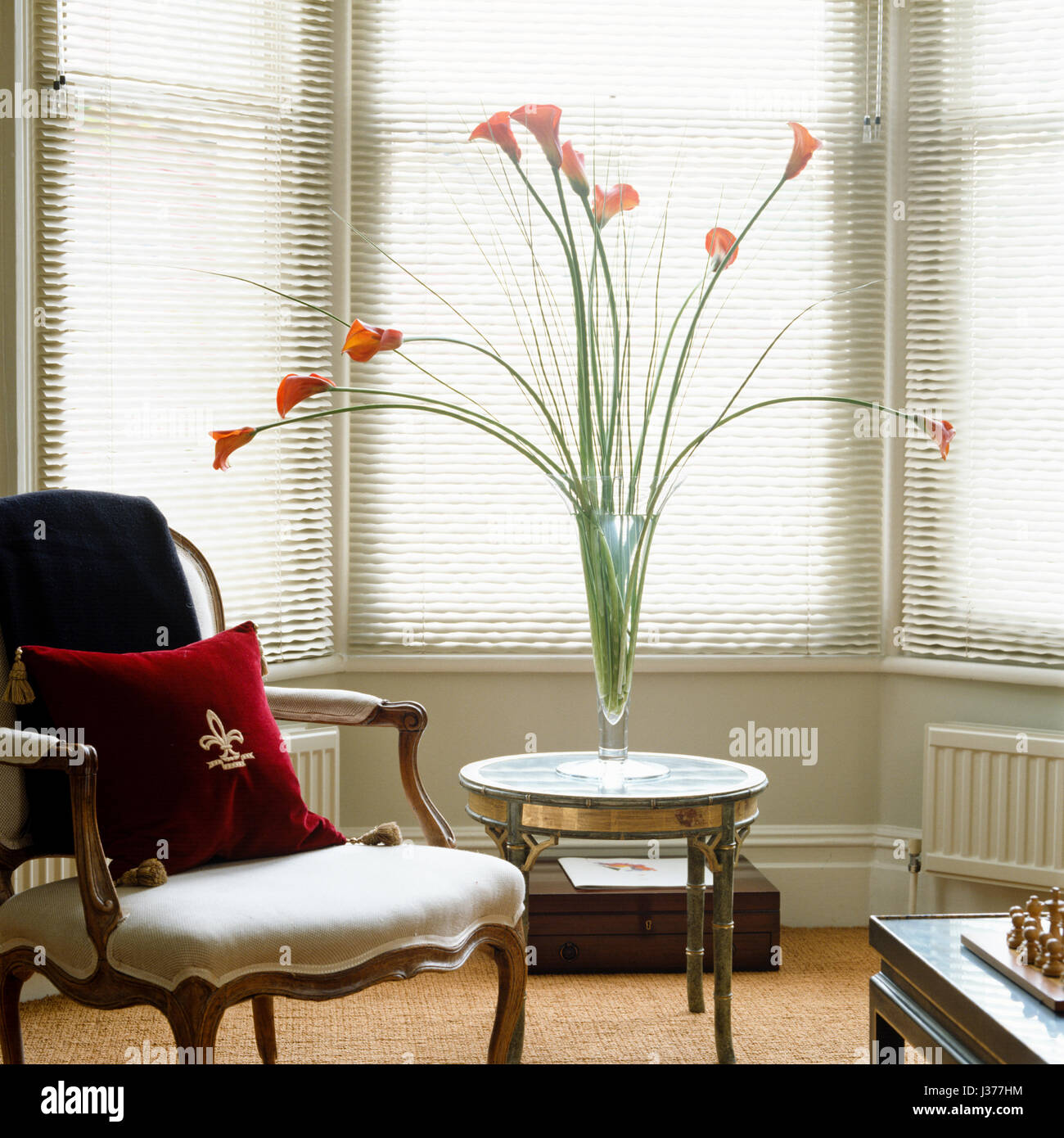 Chair beside side table with vase of flowers. Stock Photo
