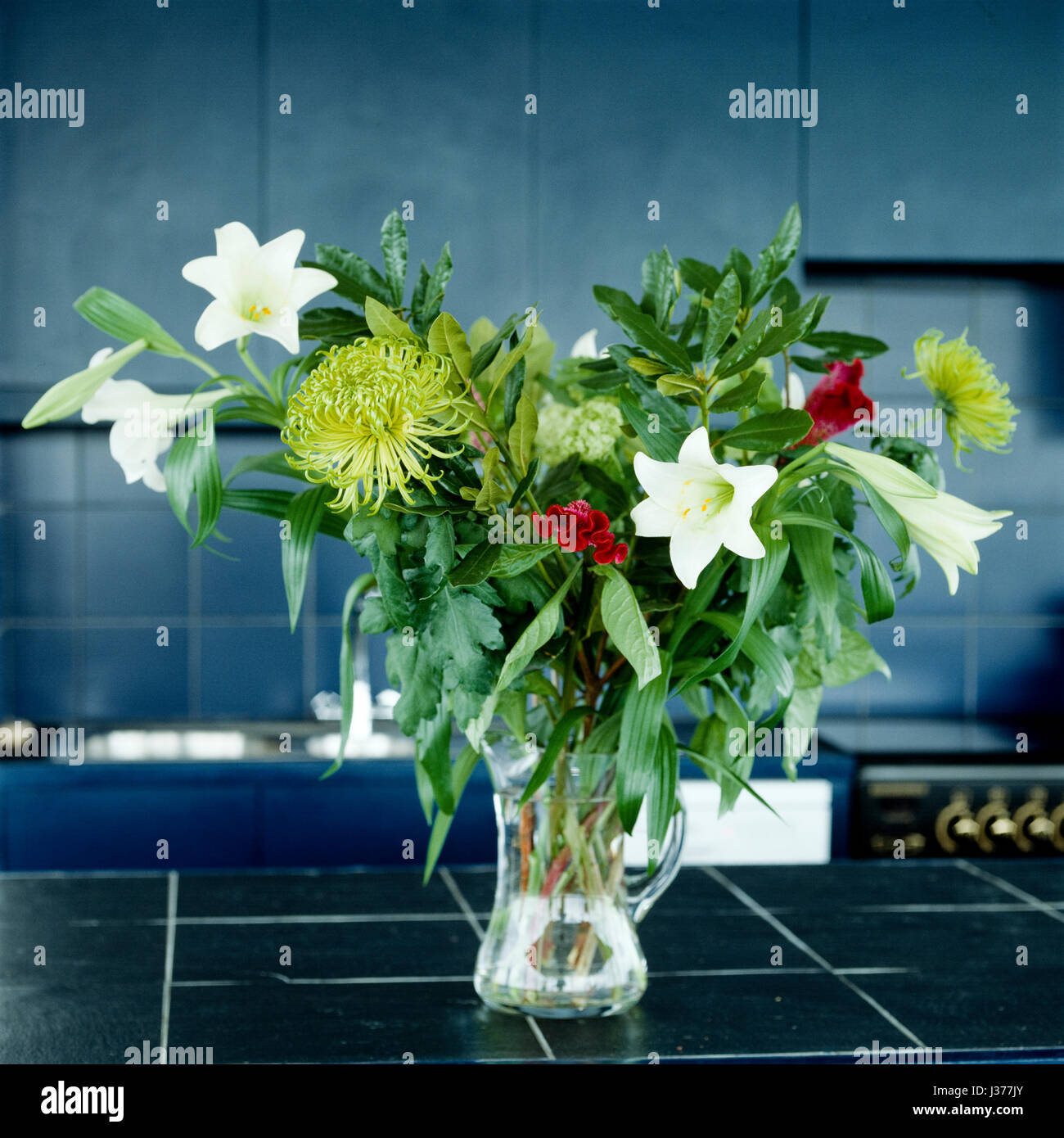 Vase of flowers on kitchen bench top. Stock Photo