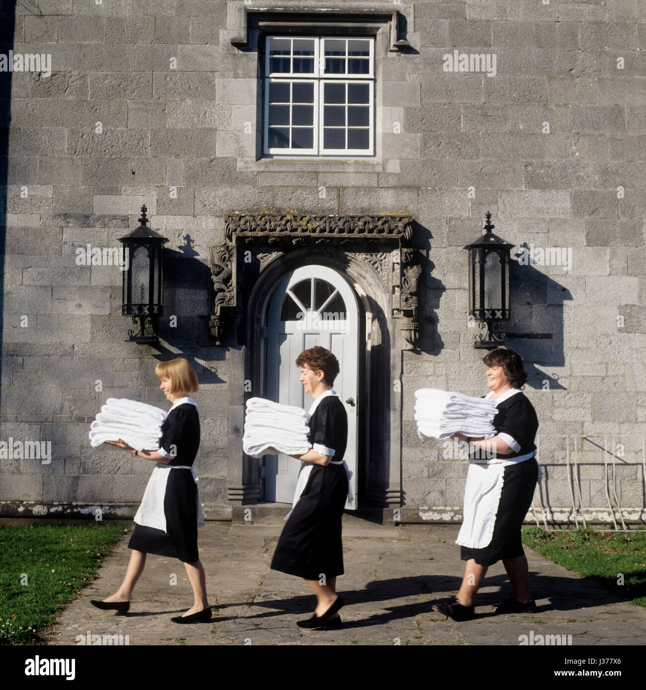 Three maids walking past the entrance of house. Stock Photo