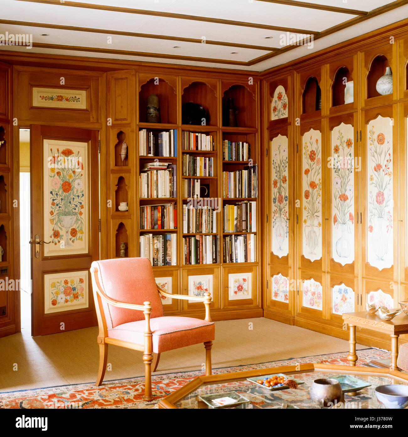 An armchair in front of wooden shelves filled with books. Stock Photo