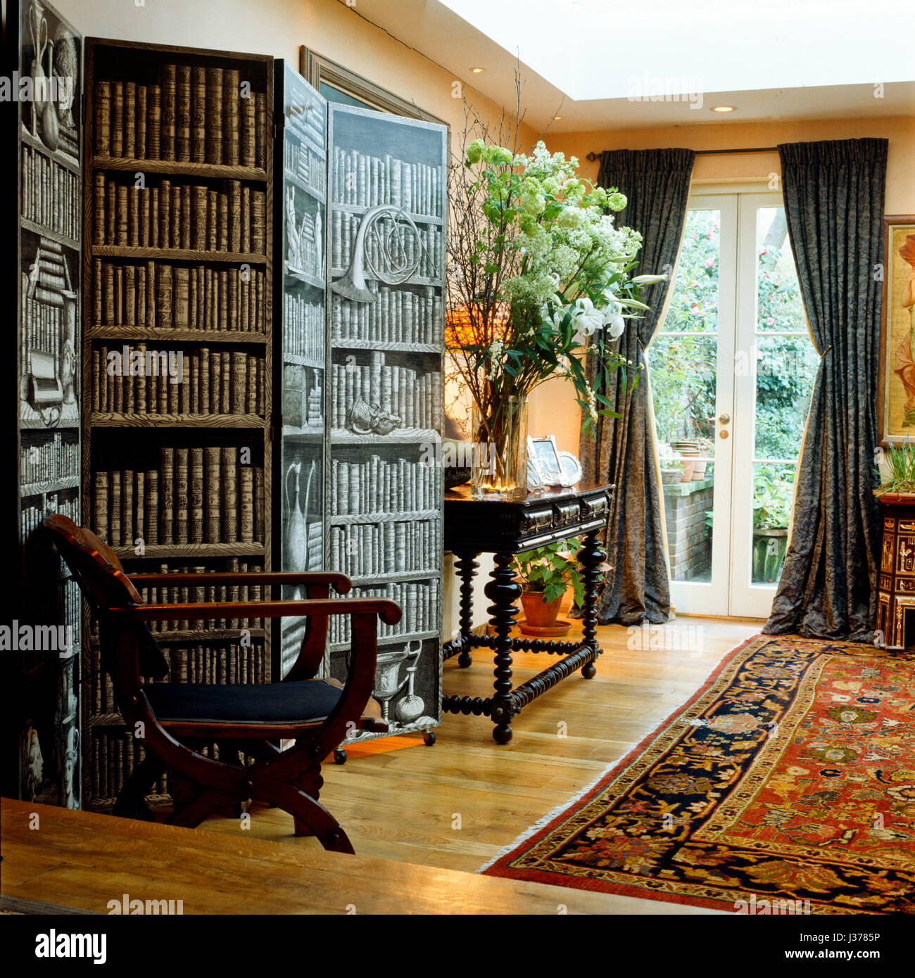 Screen depicting bookcase with table and chair Stock Photo Alamy