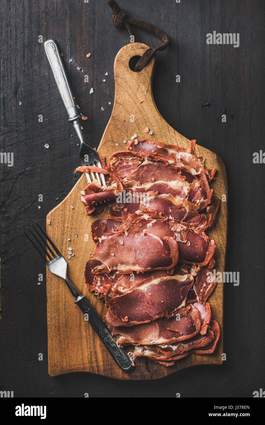 Turkish pastirma on wooden board over dark background, top view Stock Photo