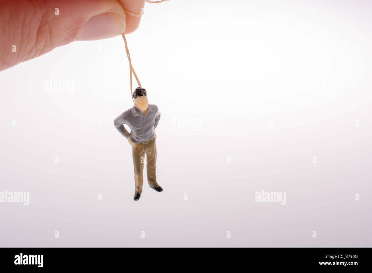 Man figurine tied with aa rope on a brown backgorund Stock Photo - Alamy