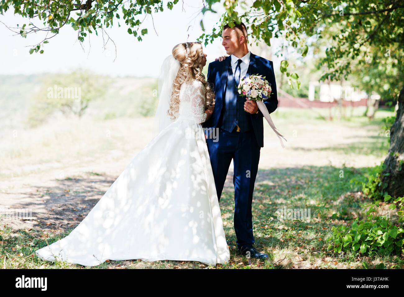 Happy wedding couple in love near trees on sunny day Stock Photo - Alamy