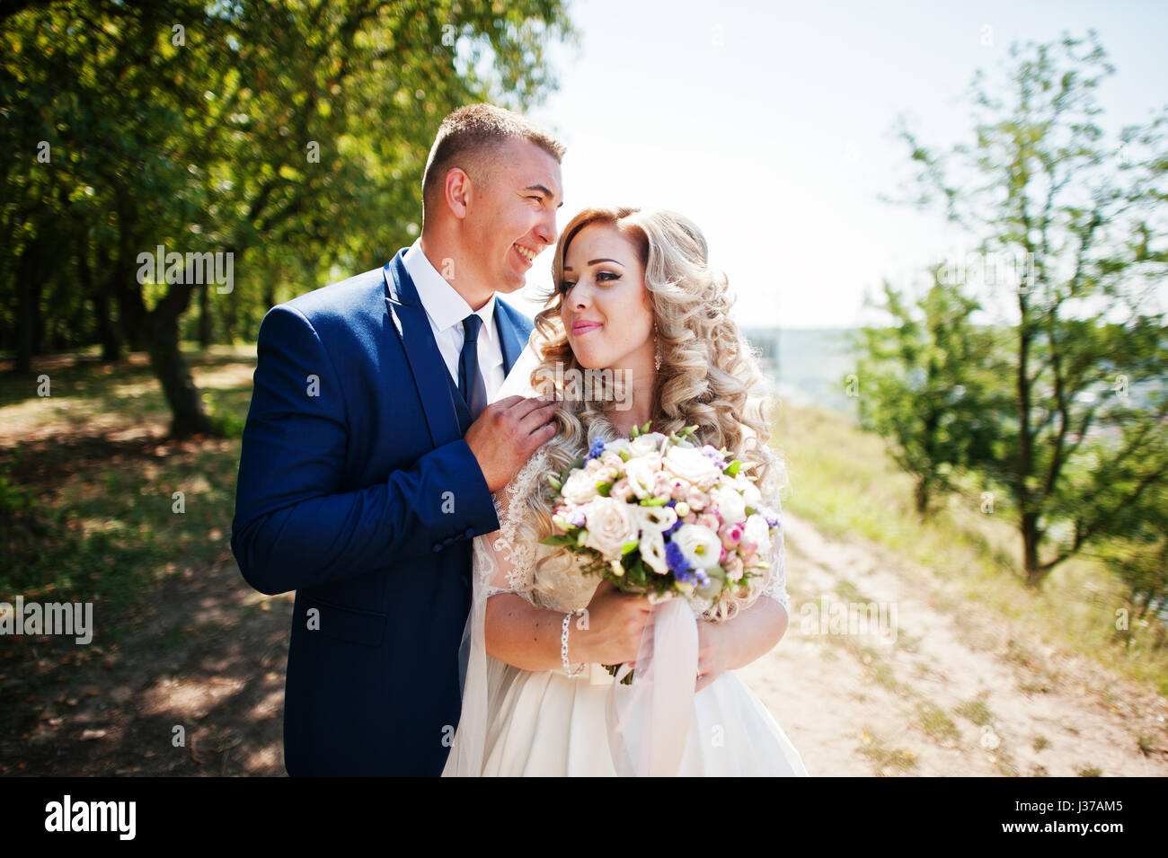 Happy wedding couple in love near trees on sunny day Stock Photo - Alamy