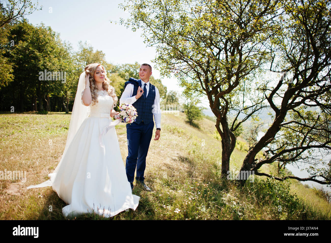Happy wedding couple in love near trees on sunny day Stock Photo - Alamy
