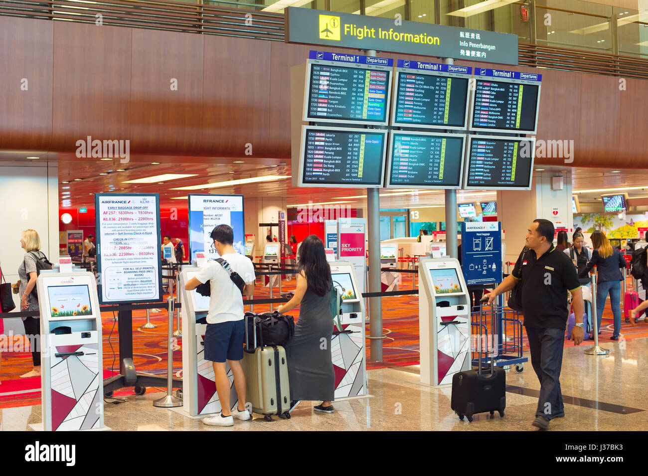 SINGAPORE - JANUARY 13, 2017: Passengers at self check-in kiosk near information board in Changi Airport. Changi Airport serves more than 100 airlines Stock Photo