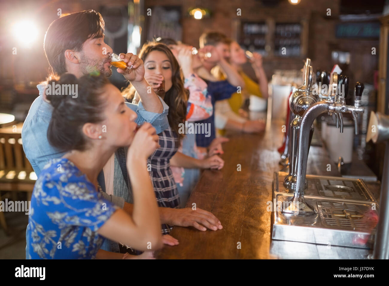 Friends drinking vodka shorts by counter in bar Stock Photo