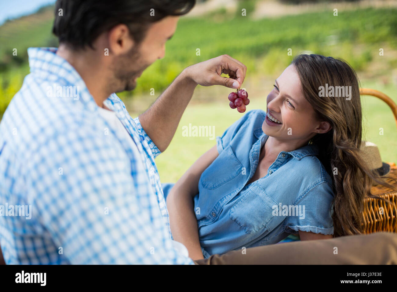 Man feeding grapes to cheerful female partner Stock Photo - Alamy