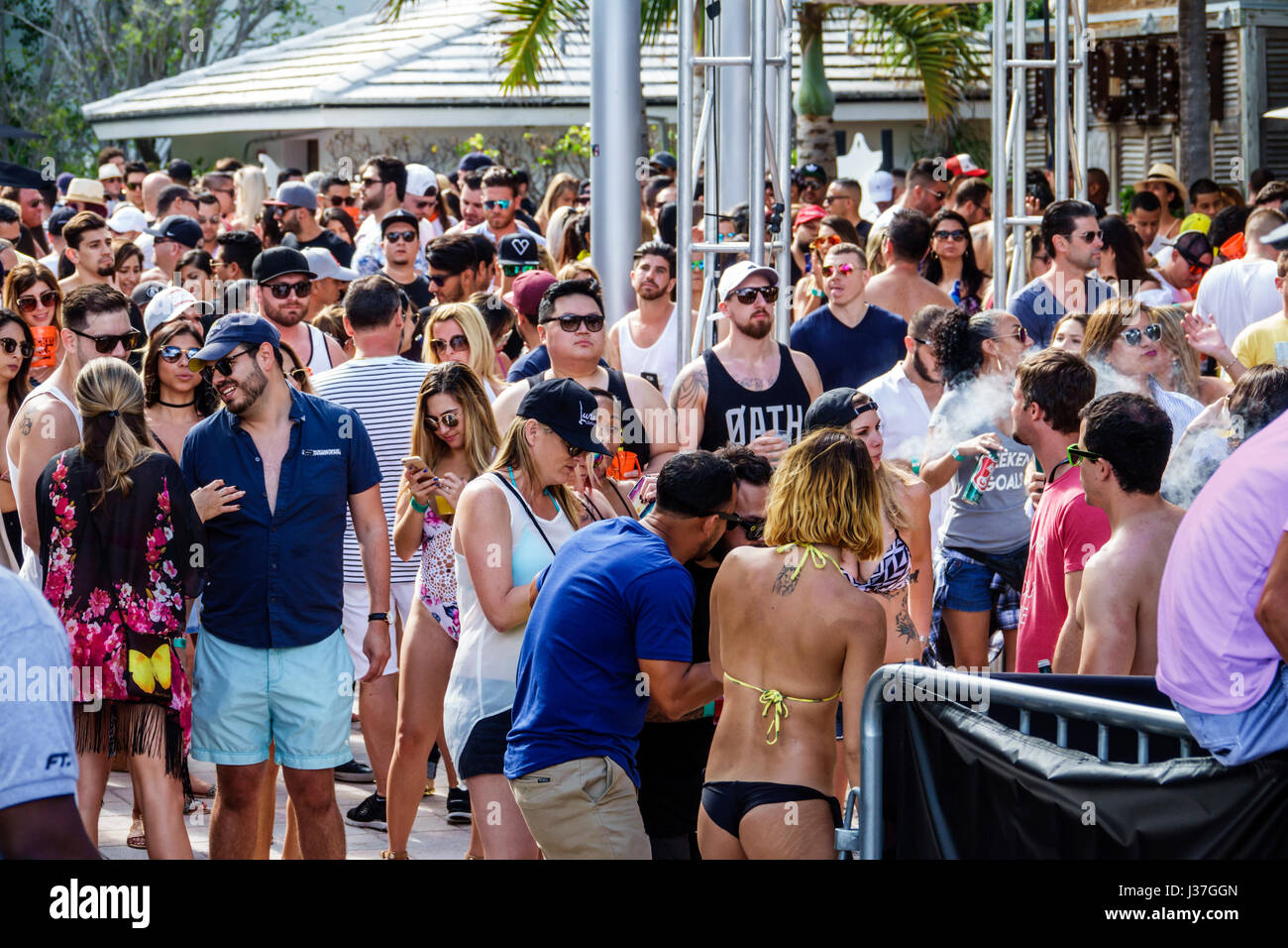 Miami Beach Florida,Miami Music Week,hotel pool party,crowd,standing,dancing,drink drinks beverage beverages drinking,young adult,men,women,visitors t Stock Photo