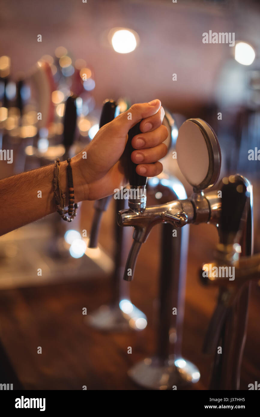 Close-up of bartender hands using beer tap in pub Stock Photo