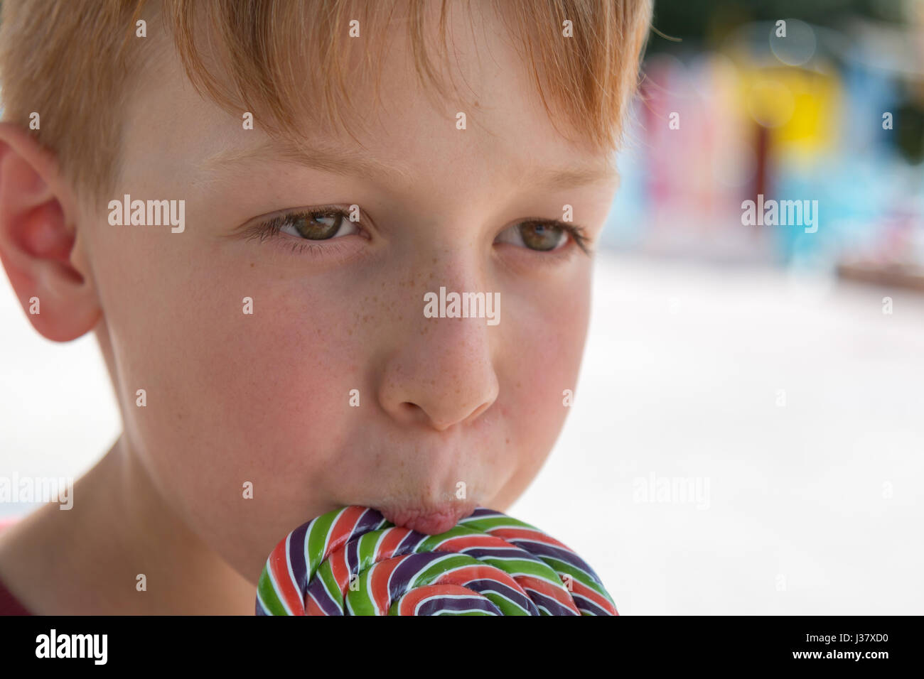 Close up of Eight Years Child Licking Colorful Round Lollipop Stock Photo