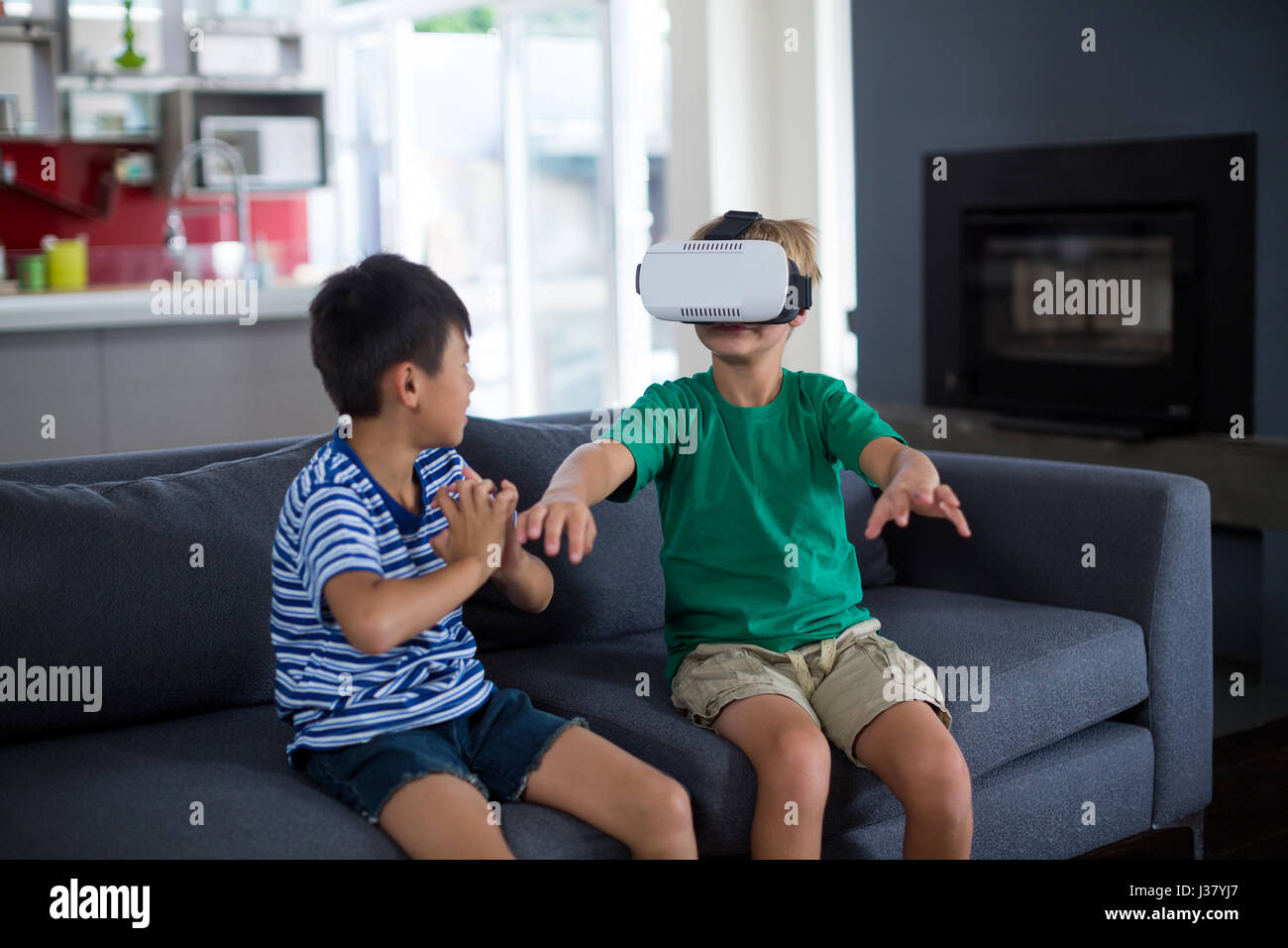 Boy looking at his brother using virtual reality headset in living room ...