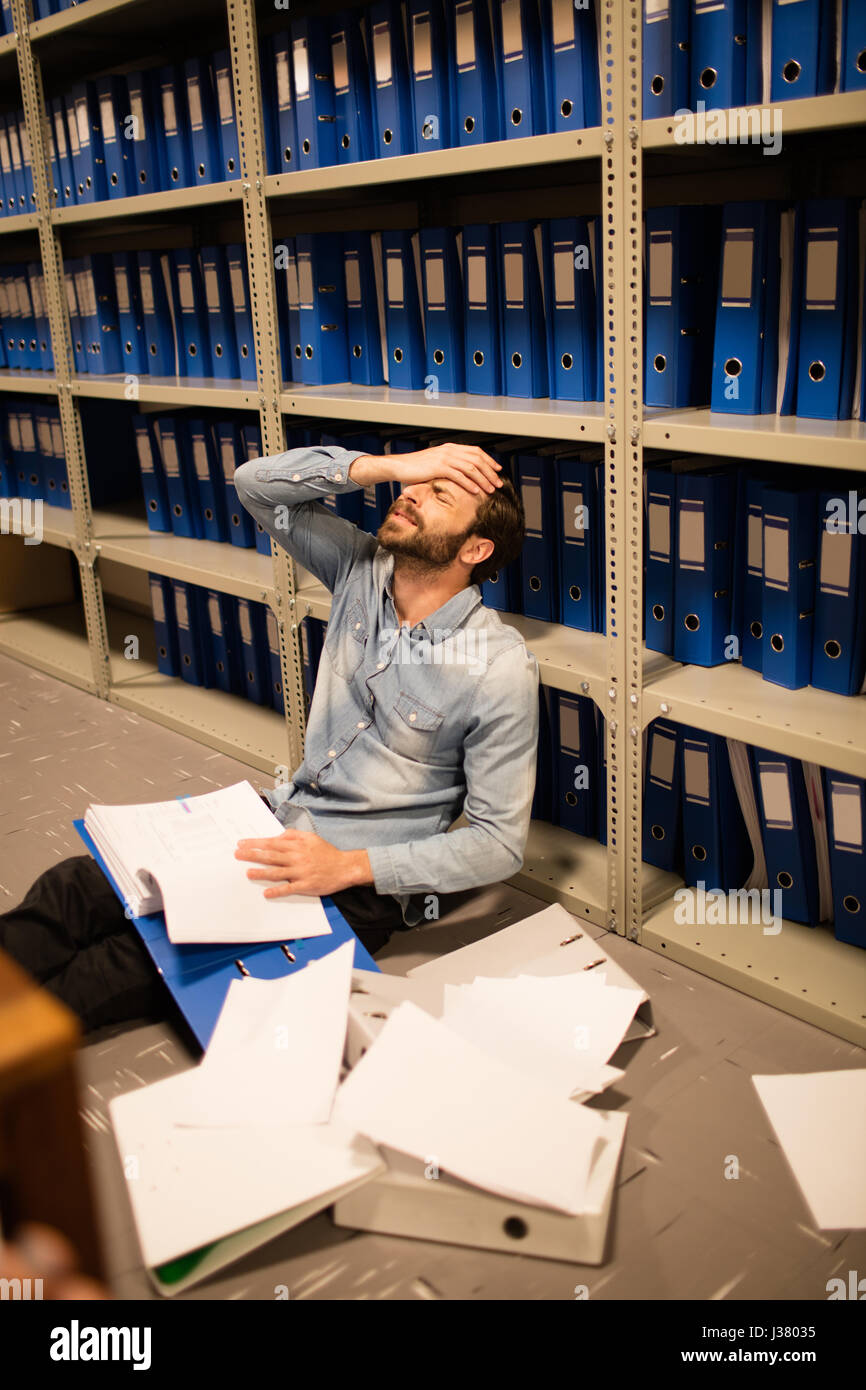 High angle view of frustrated businessman with file and papers sitting in storage room Stock Photo