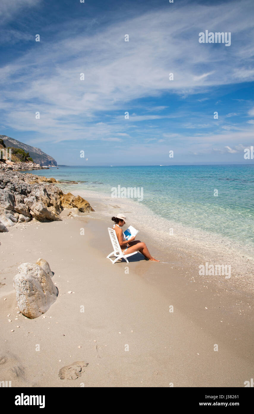 Girl reading book on the shore of Ziu Martine beach, Cala Gonone, Sardinia, Italy Stock Photo