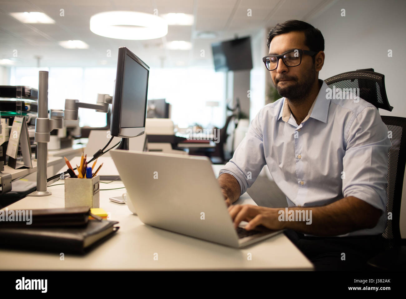 Concentrated businessman working on laptop while sitting at desk in