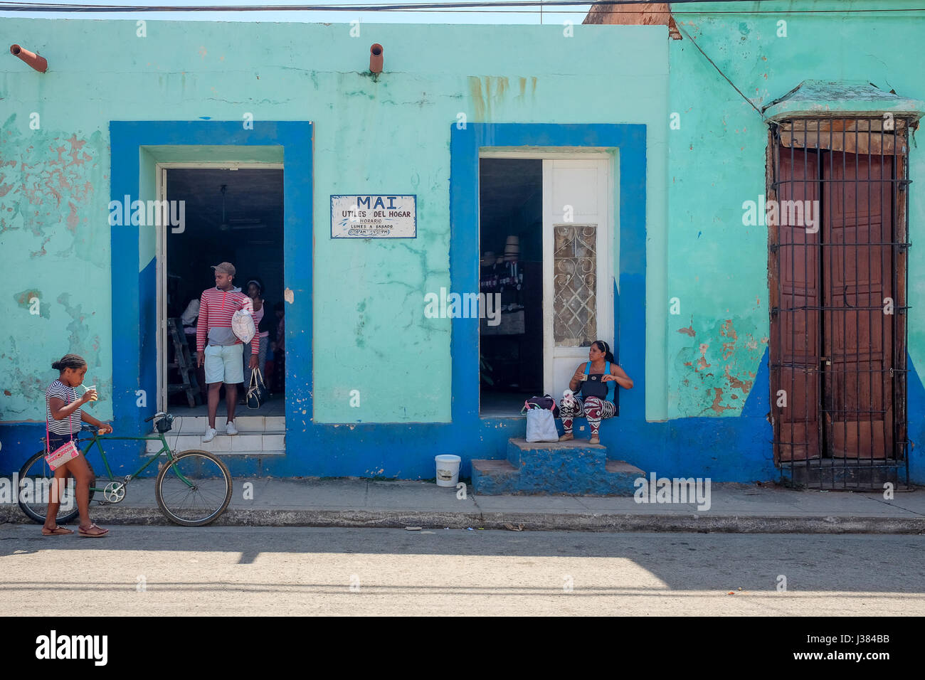 Local street life in Trinidad, Sancti Spiritus, Cuba. People gathering in front of a shop. Stock Photo