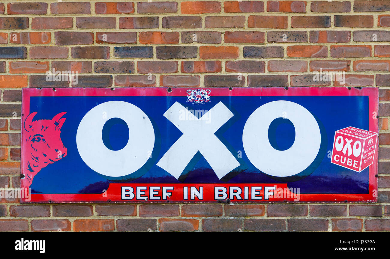Old-fashioned, vintage metallic tin advertisement for OXO Cubes on a brick wall at Tenterden Town Station, Tenterden, Kent, south-east England, UK Stock Photo