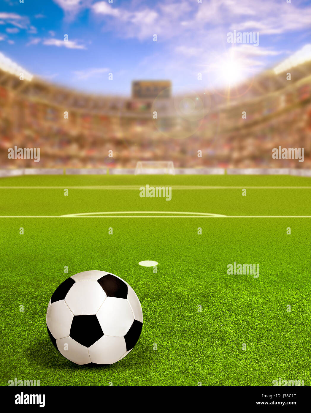 Soccer arena full of fans in the stands with football on field and deliberate sun flare for special effect. Focus on foreground and copy space. Stock Photo