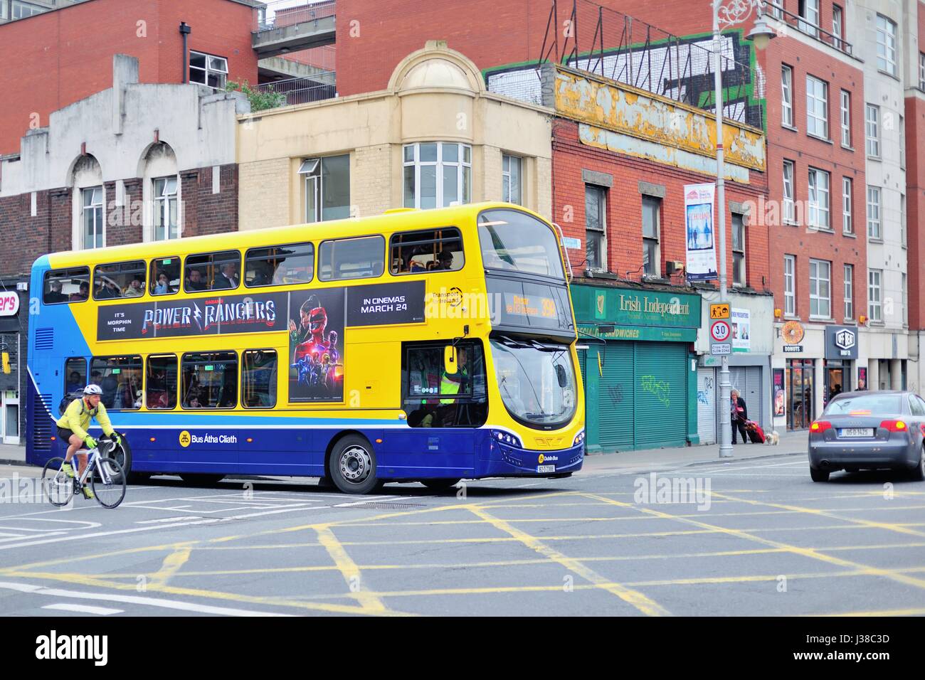 A city double-decker bus entering a Dublin, Ireland  intersection along with a cyclist in the city center. Dublin, Ireland. Stock Photo