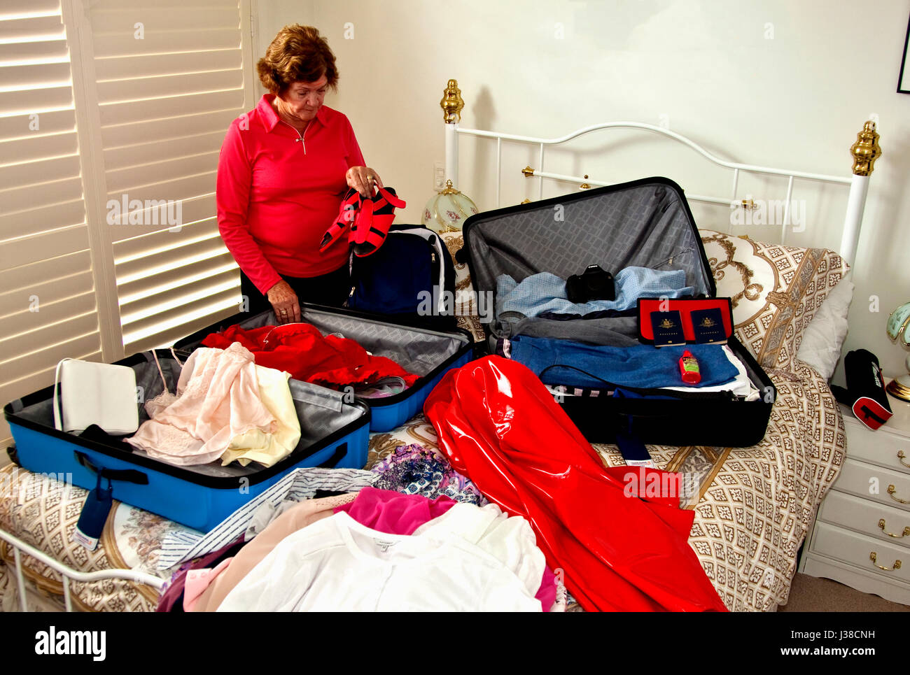 Senior woman packing suitcases for big overseas trip Stock Photo