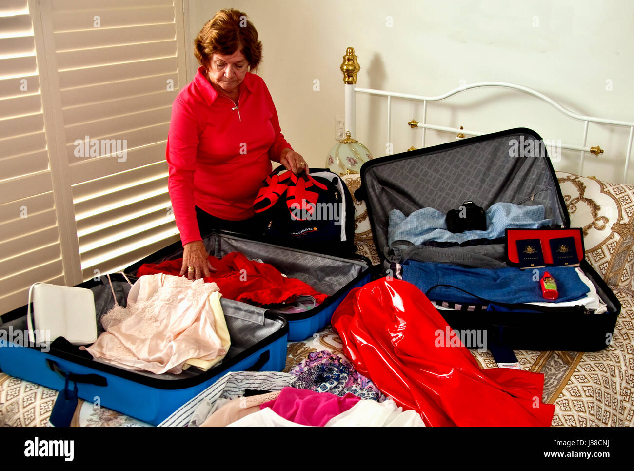 Senior woman packing suitcases for big overseas trip Stock Photo