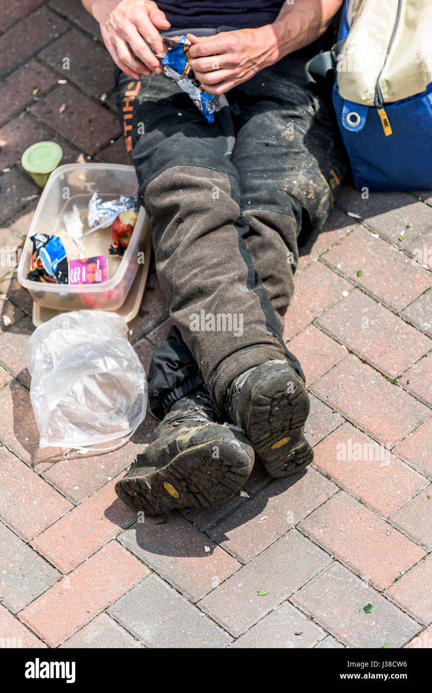 A worker relaxing during his lunch break; Worker; Manual worker; Relaxing; Lunch break; Lunch hour; Protective workwear; Safety boots Stock Photo
