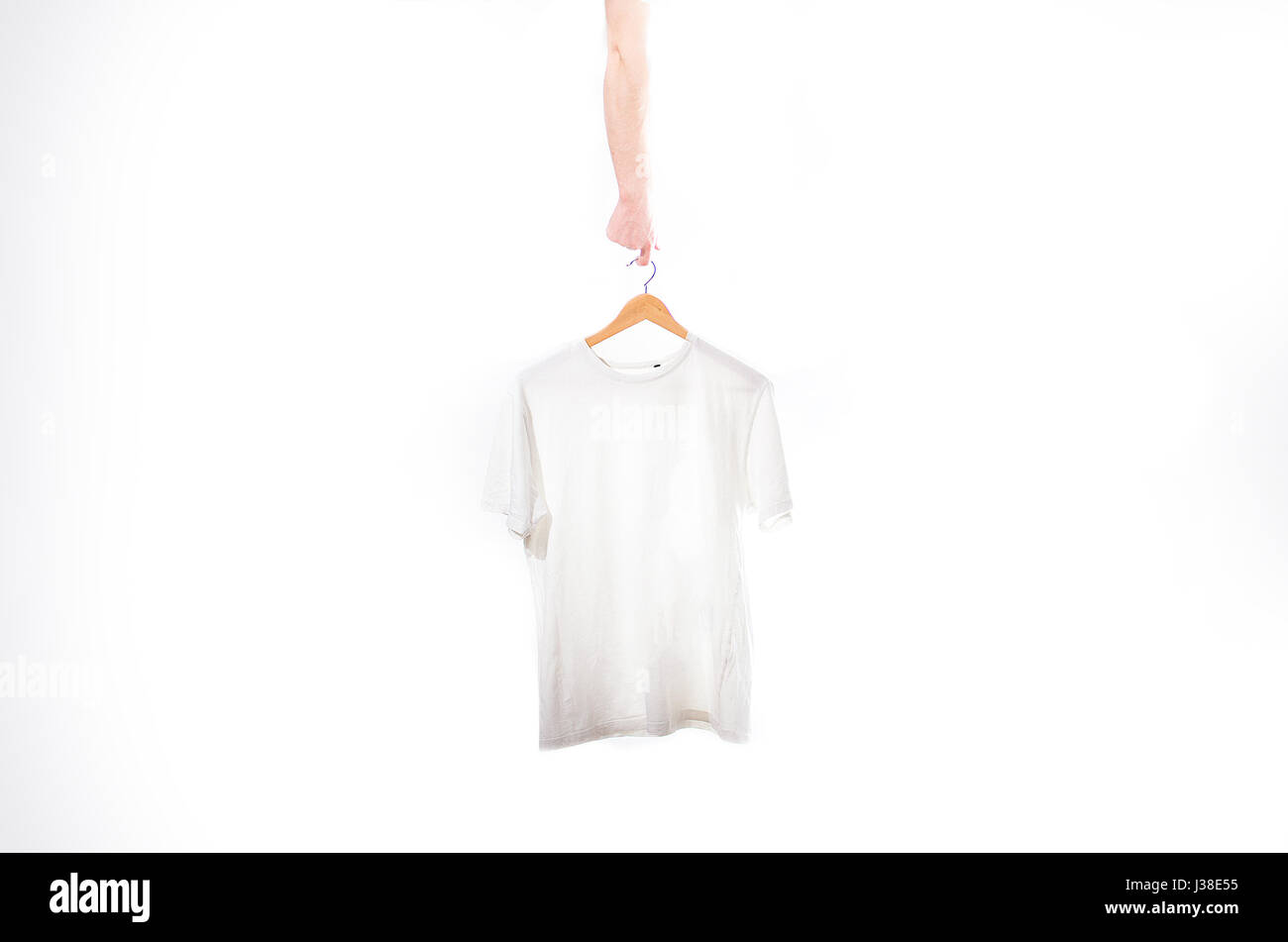 https://c8.alamy.com/comp/J38E55/hand-holds-a-white-t-shirt-on-a-hanger-on-a-white-J38E55.jpg