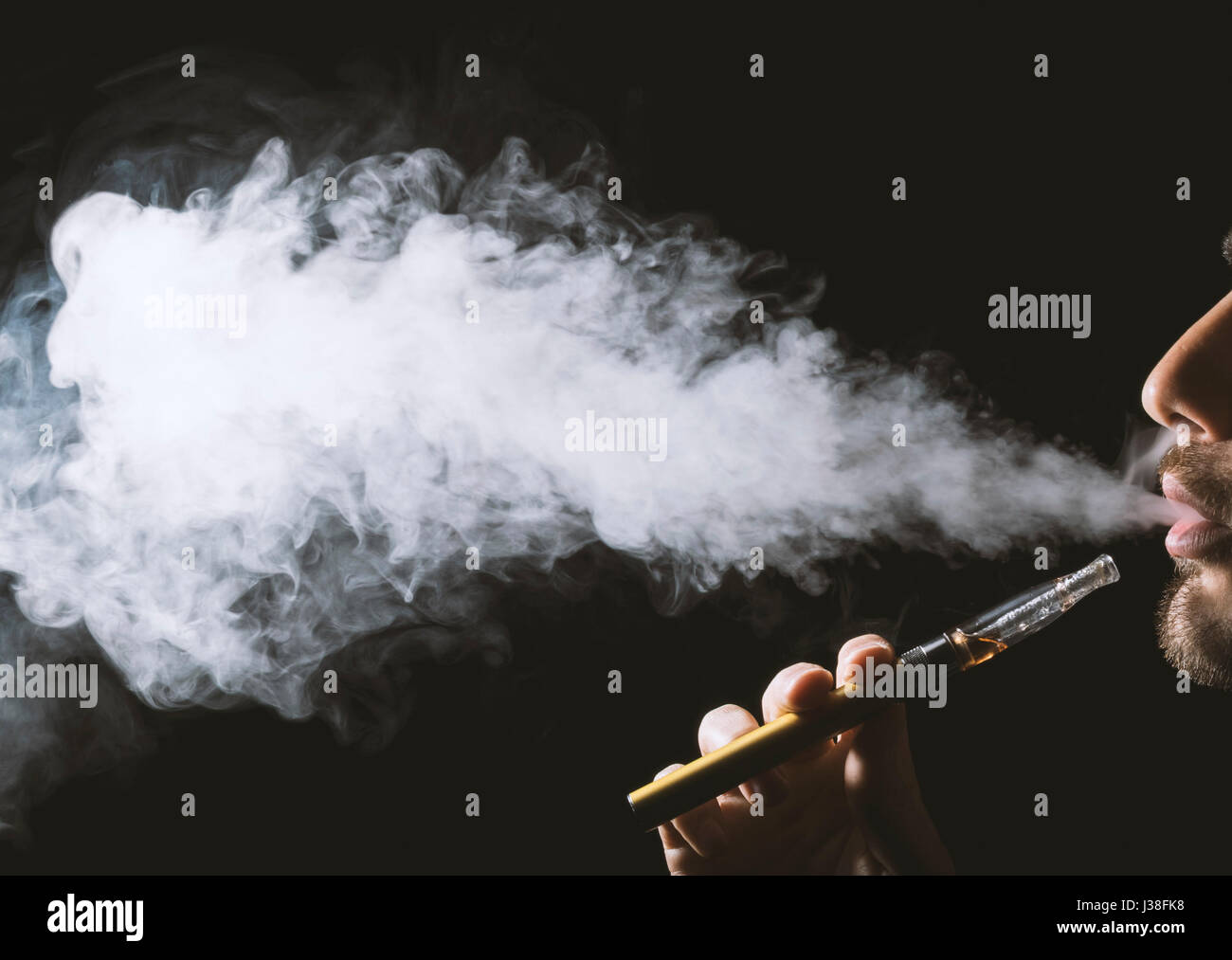 Young man holding and vaping an electronic cigarette, e-cig, ecigarette. Stock Photo
