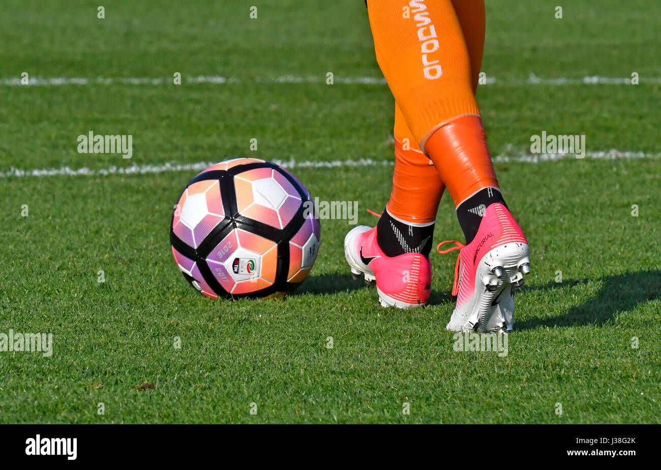 soccer player's close up legs, kicking the ball on the pitch grass. Stock Photo